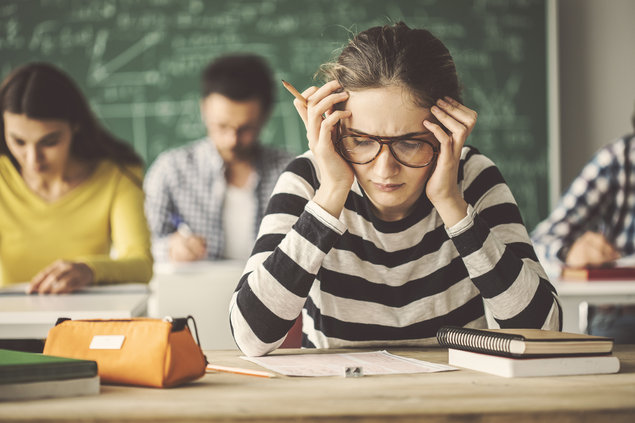 Do You Know These 9 Best Tips for Acing the ACT? high school girl wearing striped shirt worrying over a test.