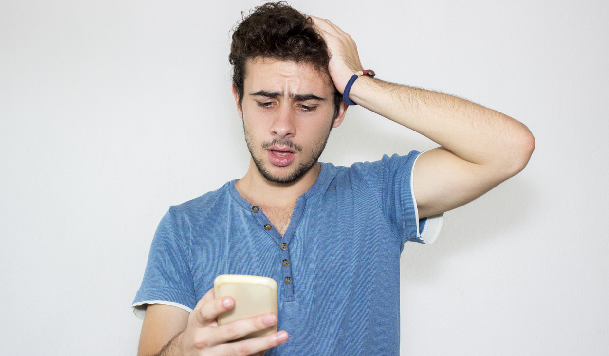 No College Early Decision? It Will Be OK Portrait of sad teenage boy reading message on his phone.