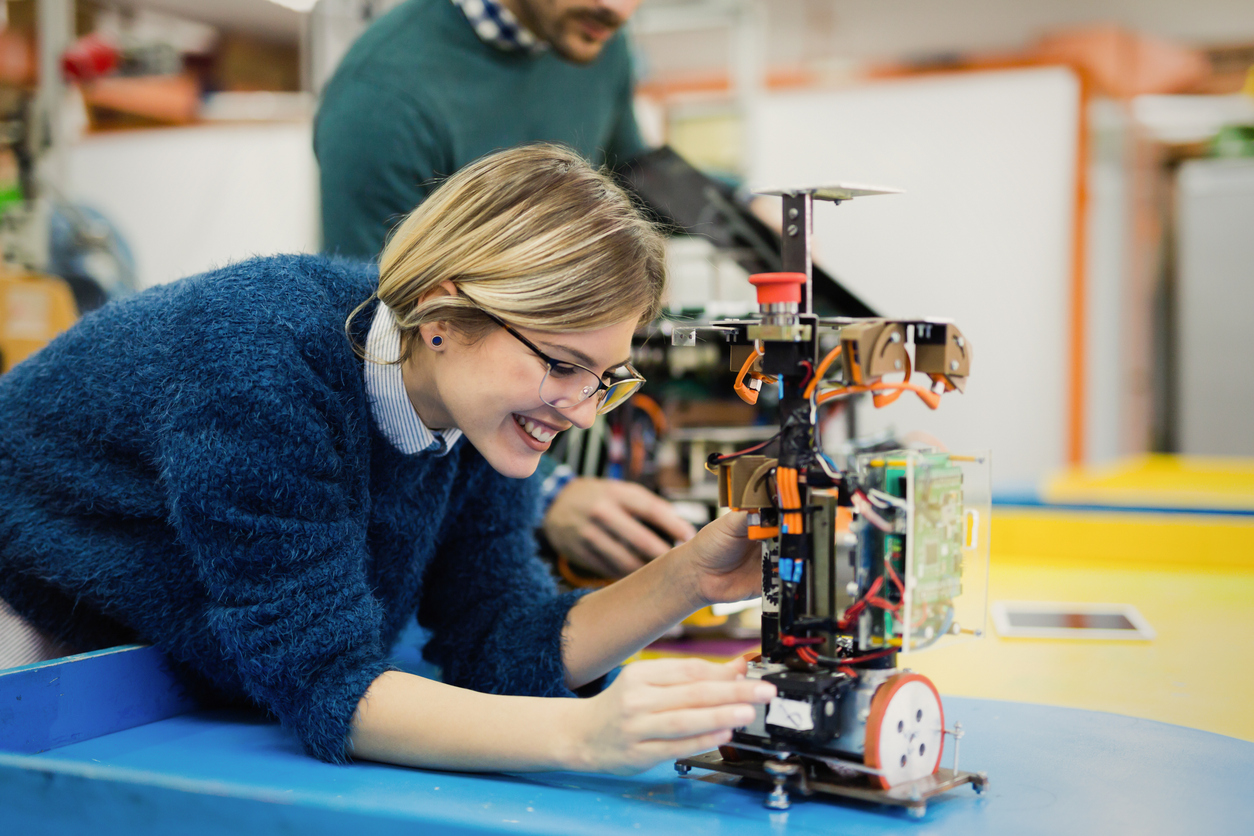 STEM High Schools: Could This Boost Your Future? Young blond woman in blue sweater working on robotics.
