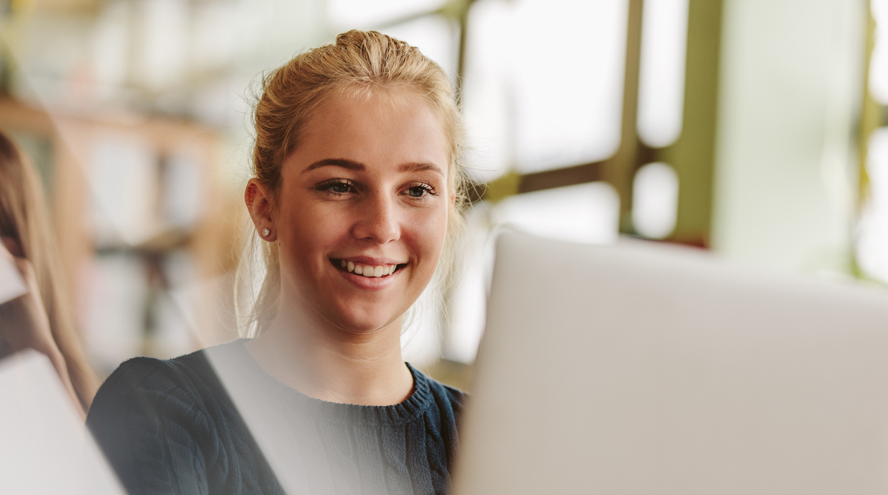 What's an IB High School and Why Consider It? Young blonde woman studying at computer.